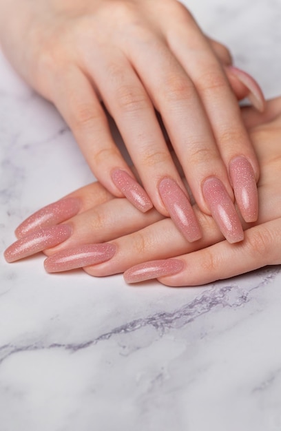 Des mains féminines avec une belle manucure sur fond de marbre