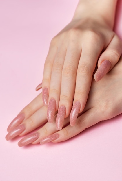 Des mains féminines avec une belle manucure sur fond rose