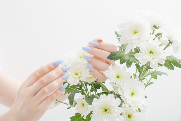 Mains féminines avec de belles fleurs de manucure et de chrysanthème