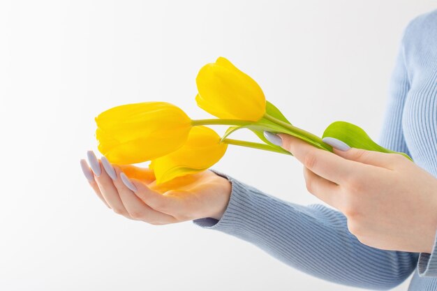 Mains féminines avec de belles fleurs de manucure et de tulipes sur fond blanc