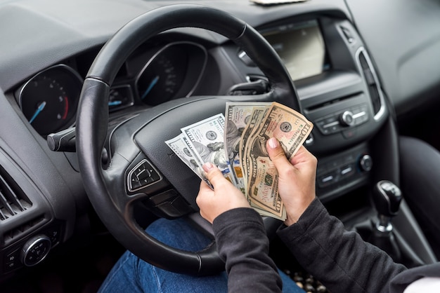 Mains féminines avec des billets en dollars en gros plan sur le volant