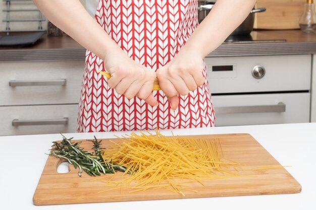 Des mains féminines cassent des nouilles spaghetti