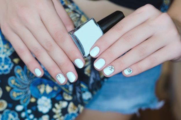 Mains féminines avec la conception des ongles bleu clair