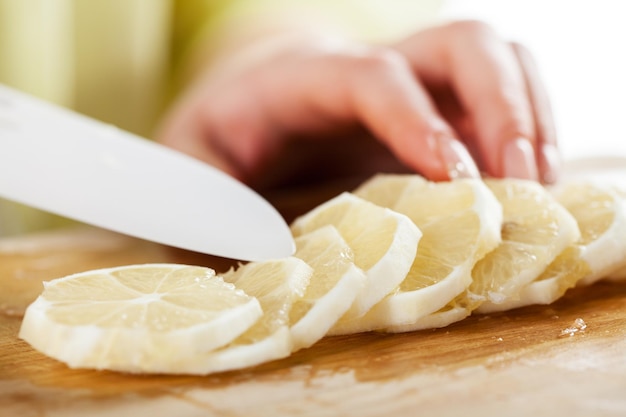 Mains féminines Couper le citron dans une cuisine. Fermer. Mise au point sélective.