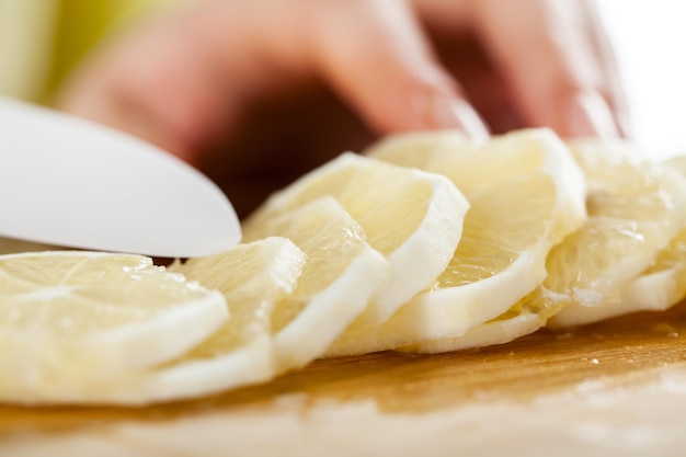 Mains féminines Couper du citron dans une cuisine. Fermer. Mise au point sélective.