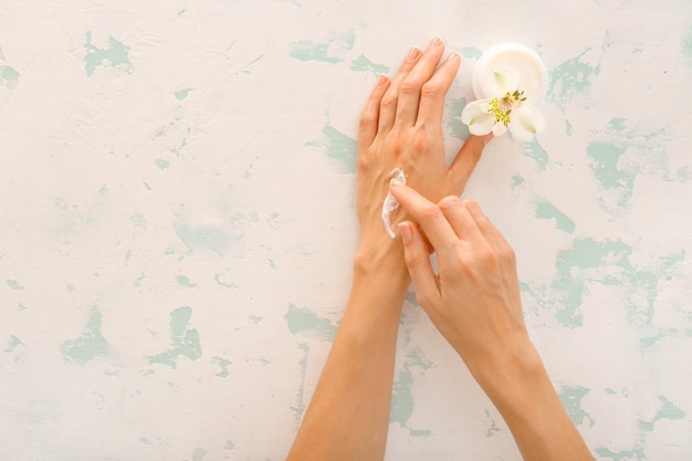 Mains féminines avec crème naturelle sur beige