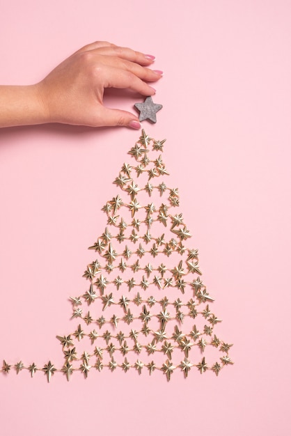 Mains féminines décorant le sapin de Noël doré en perles sur rose. Vue d'en-haut. Mise à plat