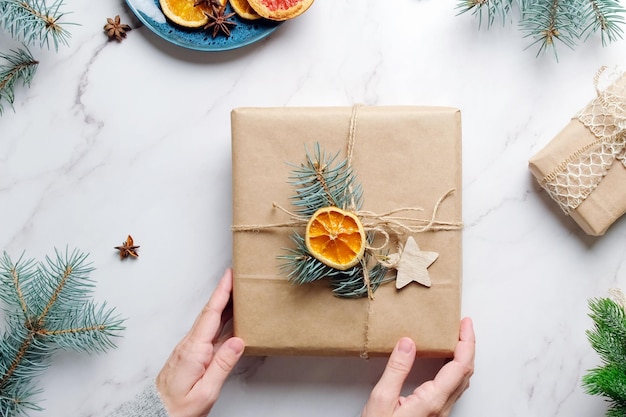 Les mains féminines décorent le cadeau de Noël