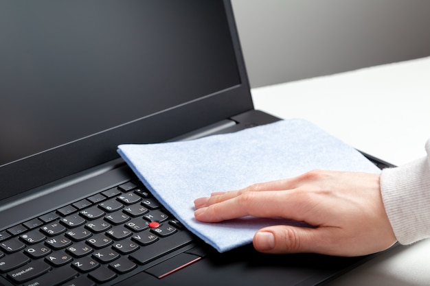 Mains féminines désinfectant le clavier d'un ordinateur portable à l'aide de lingettes désinfectantes humides. Une femme nettoyant le clavier des virus bactéries empêche le coronavirus covid. Nouvelles surfaces de travail d'ordinateur portable de nettoyage normal.