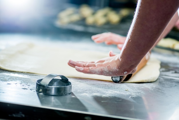 Les mains féminines du boulanger roulent la pâte