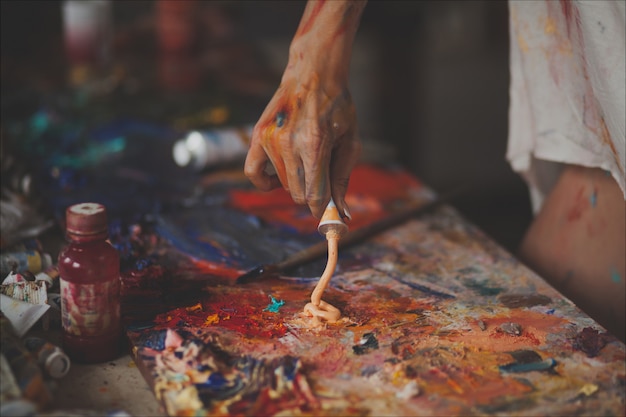 Mains féminines du peintre avec des pinceaux, des peintures et une palette pour le dessin