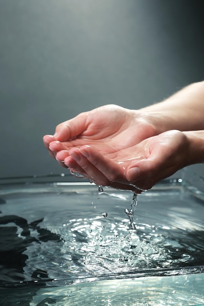 Mains féminines avec des éclaboussures d'eau sur fond sombre