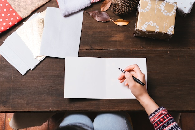 Mains féminines, écrivant des cartes de Noël sur la table en bois