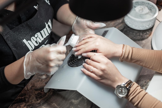 Les mains féminines font une manucure dans un salon de beauté gros plan Flux de travail de manucure maître