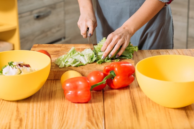 Mains féminines hacher les légumes dans la cuisine