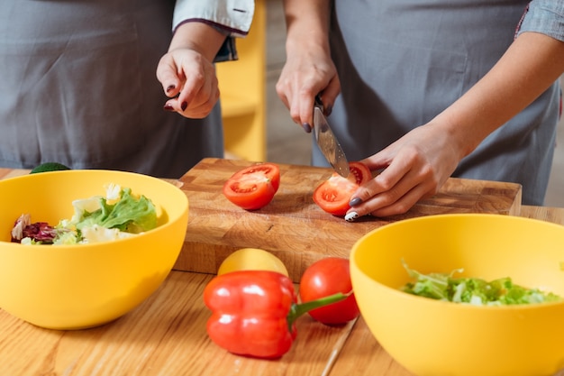 Mains féminines hacher les légumes dans la cuisine