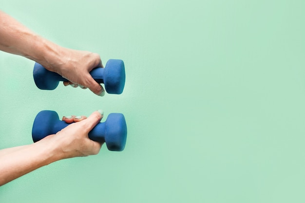 Mains féminines avec haltère bleu sur fond vert