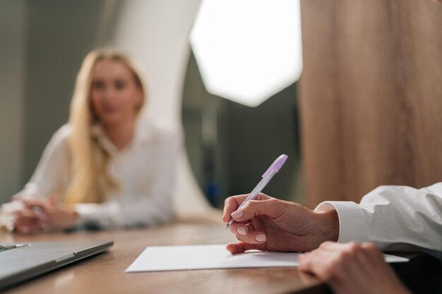 Des mains féminines irréconnaissables tenant un stylo capables de mettre leur nom sur un contrat d'assurance papier