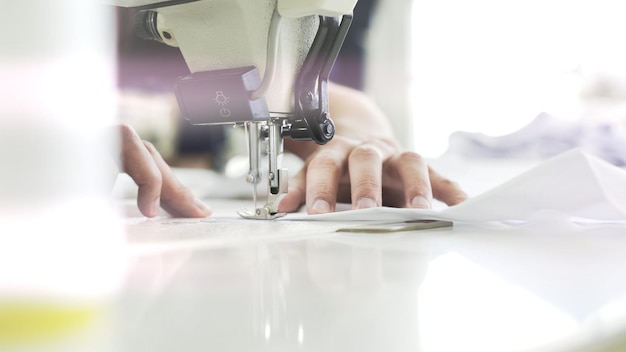 Mains féminines sur la lumière parasite de la machine à coudre blanche