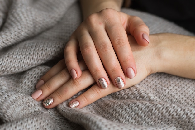 Mains féminines avec manucure et ongles polis roses