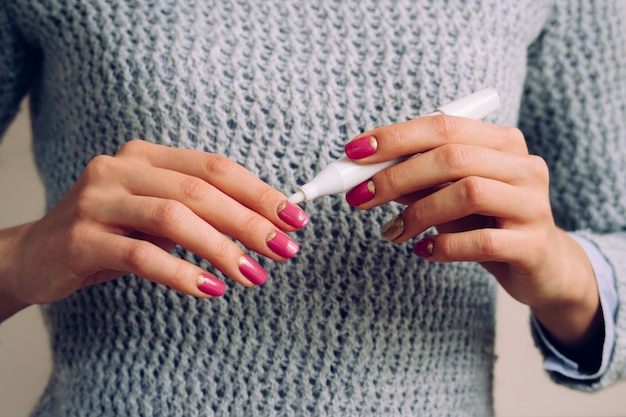 Mains féminines avec manucure rose tenant un produit cosmétique