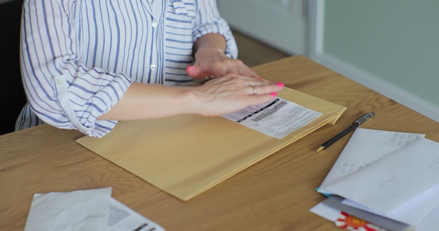 Les mains féminines mettent la lettre dans l'enveloppe du formulaire de retour La femme envoie un formulaire de retournement par lettre