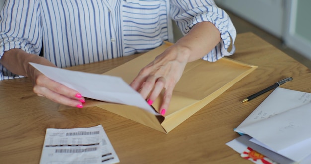 Les mains féminines mettent la lettre dans l'enveloppe du formulaire de retour La femme envoie un formulaire de retournement par lettre