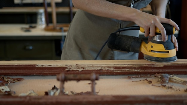 Photo mains féminines meulant les travaux de restauration de la porte en bois