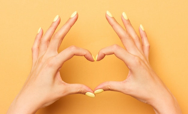 Des mains féminines montrent un symbole de coeur isolé.