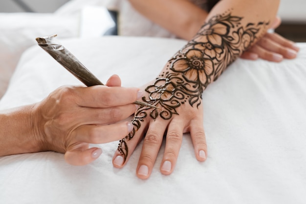 Mains féminines avec motif mehendi de fleurs artiste peinture au henné