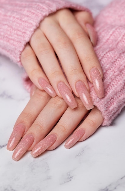Mains féminines avec un motif d'ongle rose Manicure au vernis à ongles rose sur fond de marbre