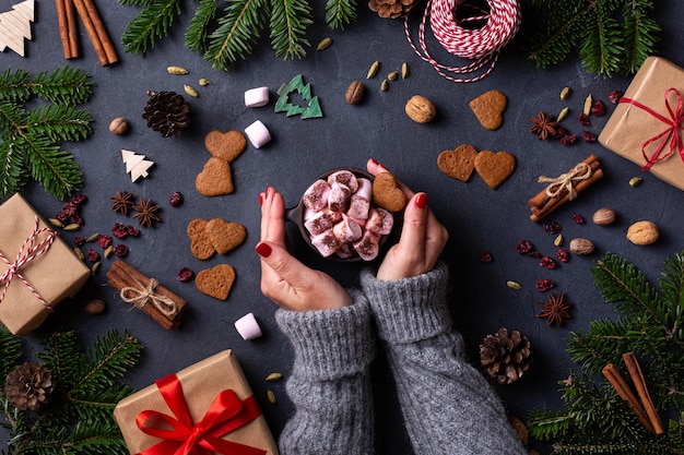 Mains féminines de Noël avec des coffrets cadeaux et une tasse de cacao