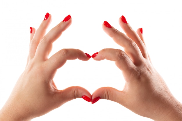 Mains féminines avec des ongles rouges en forme de coeur isolé sur blanc