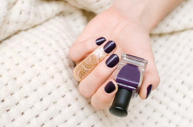 Mains féminines avec des ongles violet foncé