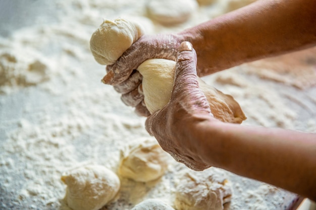 Photo des mains féminines pétrissant des pains crus faits maison sur la table processus de cuisson maison