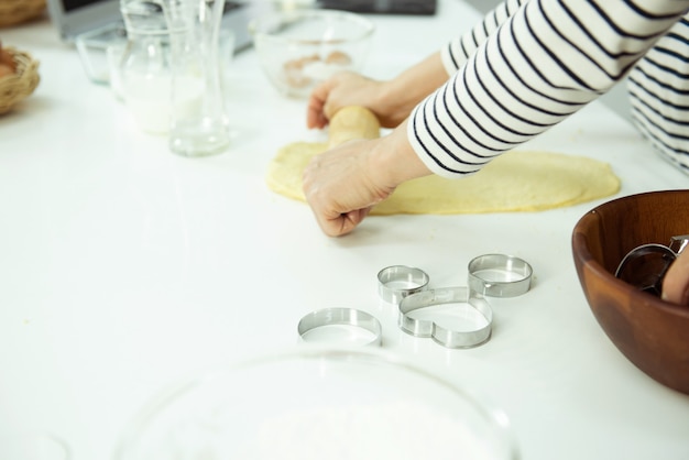 Des Mains Féminines Pétrissent La Pâte Sur Une Table Blanche, Bel éclairage Directionnel. Concept De Cuisson à Domicile Et De Confort.