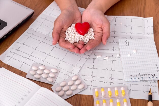 Mains féminines avec pilules blanches et coeur rouge