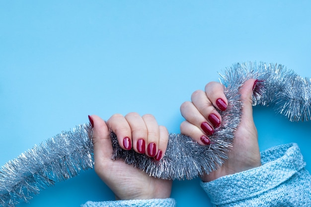 Mains féminines en pull bleu avec une belle manucure brillante