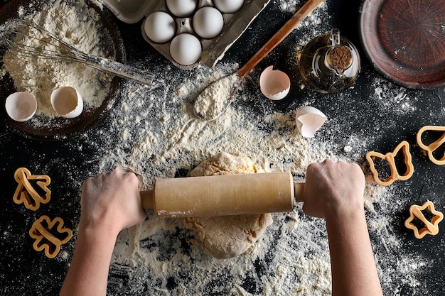 Mains Féminines Roulant La Pâte Avec Un Rouleau à Pâtisserie Sur Une Table Noire Vue De Dessus