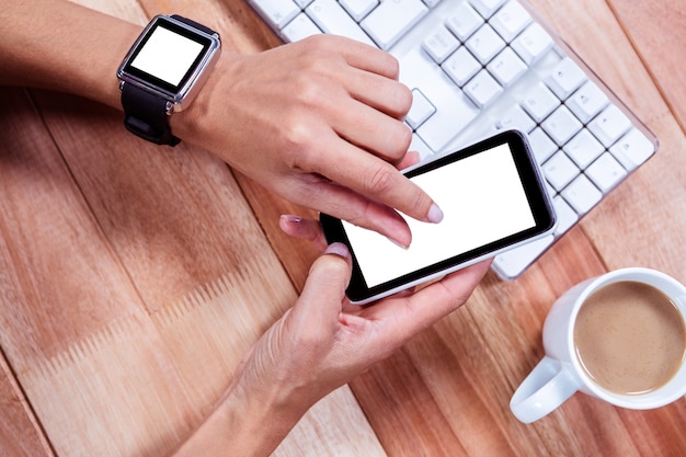 Mains féminines avec smartwatch en utilisant un smartphone