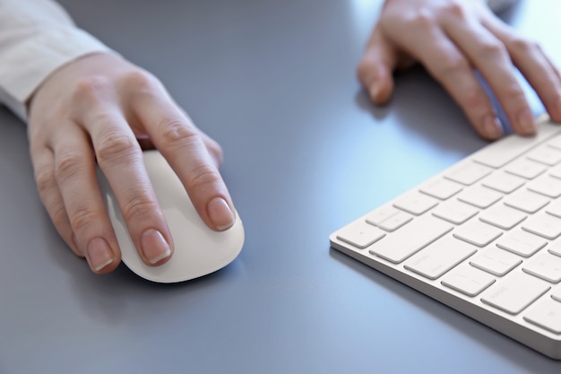 Mains féminines avec souris et clavier d'ordinateur sur tableau gris