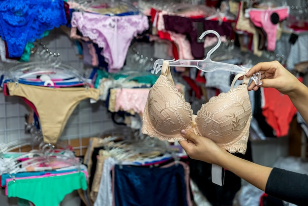 Mains féminines avec soutien-gorge beige en magasin de sous-vêtements