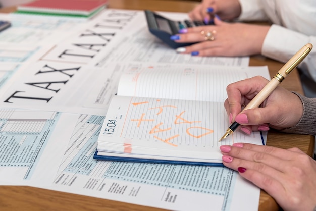 Mains féminines avec stylo et calculatrice sur formulaire 1040