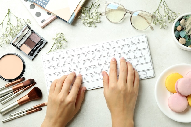 Mains féminines tapant sur le clavier sur fond avec accessoires femme