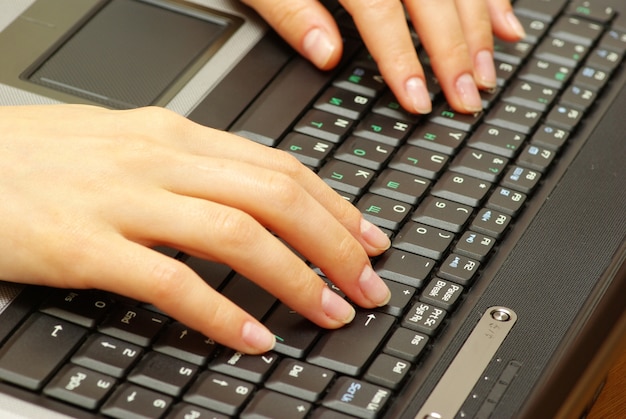 Mains féminines tapant sur le clavier d'ordinateur portable