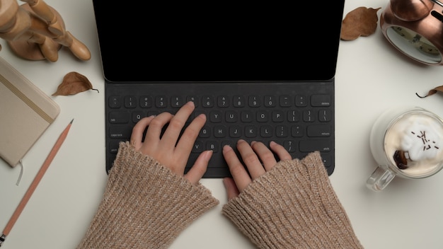 Mains féminines tapant sur le clavier de la tablette numérique