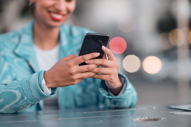 Mains féminines tapant sur un téléphone et discutant sur les réseaux sociaux à l'extérieur dans un café