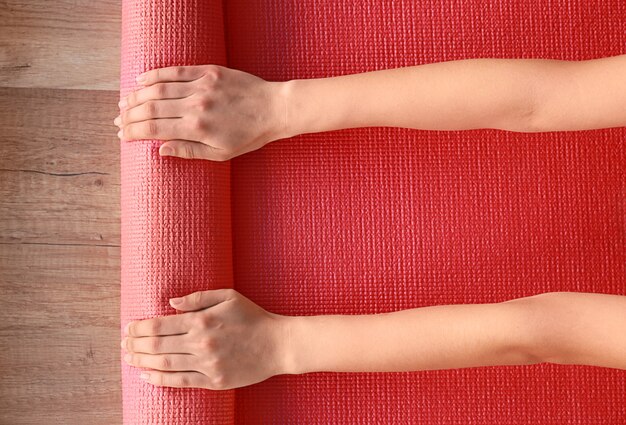 Mains féminines avec tapis de yoga, vue de dessus