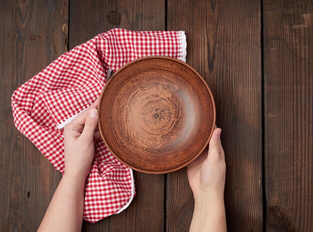 mains féminines tenant une assiette d'argile ronde vide