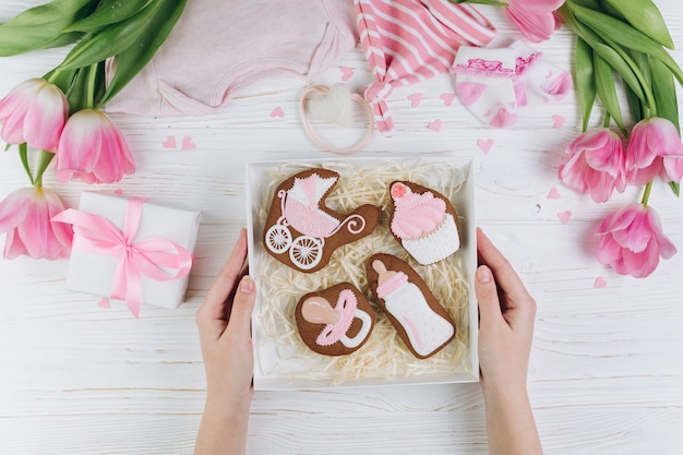 Mains féminines tenant la boîte avec des cookies. Une composition pour les nouveau-nés